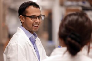 A man laughs with a member of his research team in the lab.